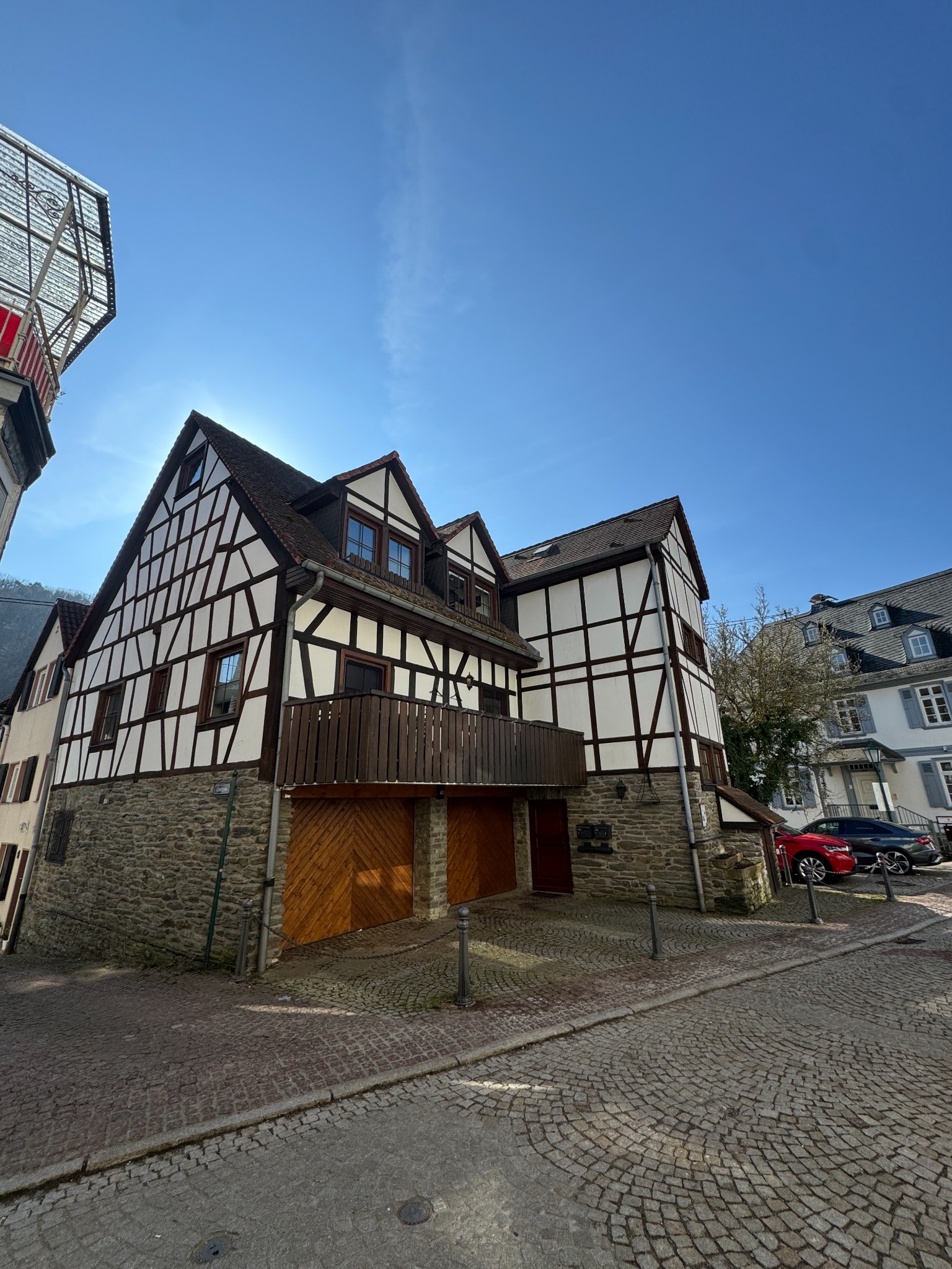 Außenansicht des Fachwerkhauses mit sichtbaren Holzbalken, Balkon und Natursteinsockel